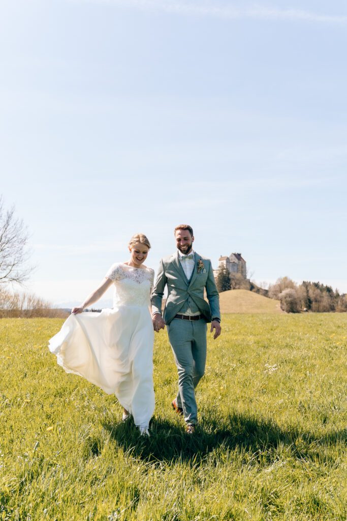 Laufendes Brautpaar auf Wiese vor Waldburg - Hochzeitsfotografie Bodensee