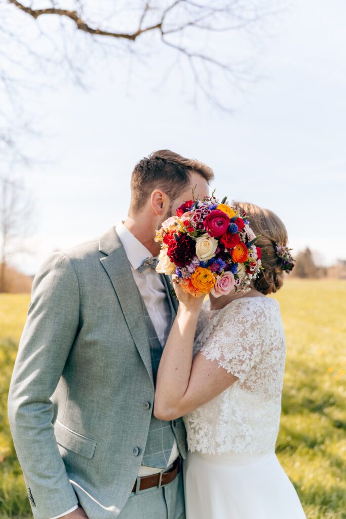 Verliebtes Hochzeitspaar versteckt sich hinter Blumenstrauß - Hochzeitsfotografie Bodensee